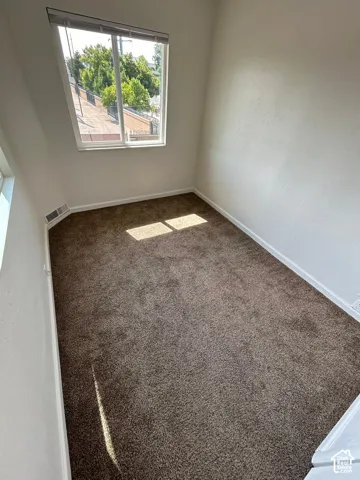 Room featuring wall-to-wall carpeting, neutral interior paint, and a sliding window with horizontal blinds