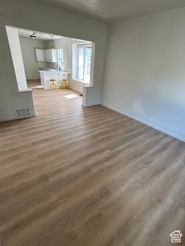 Wood-finish flooring, neutral wall tones, white cabinetry, countertop with integrated sink, and bay window