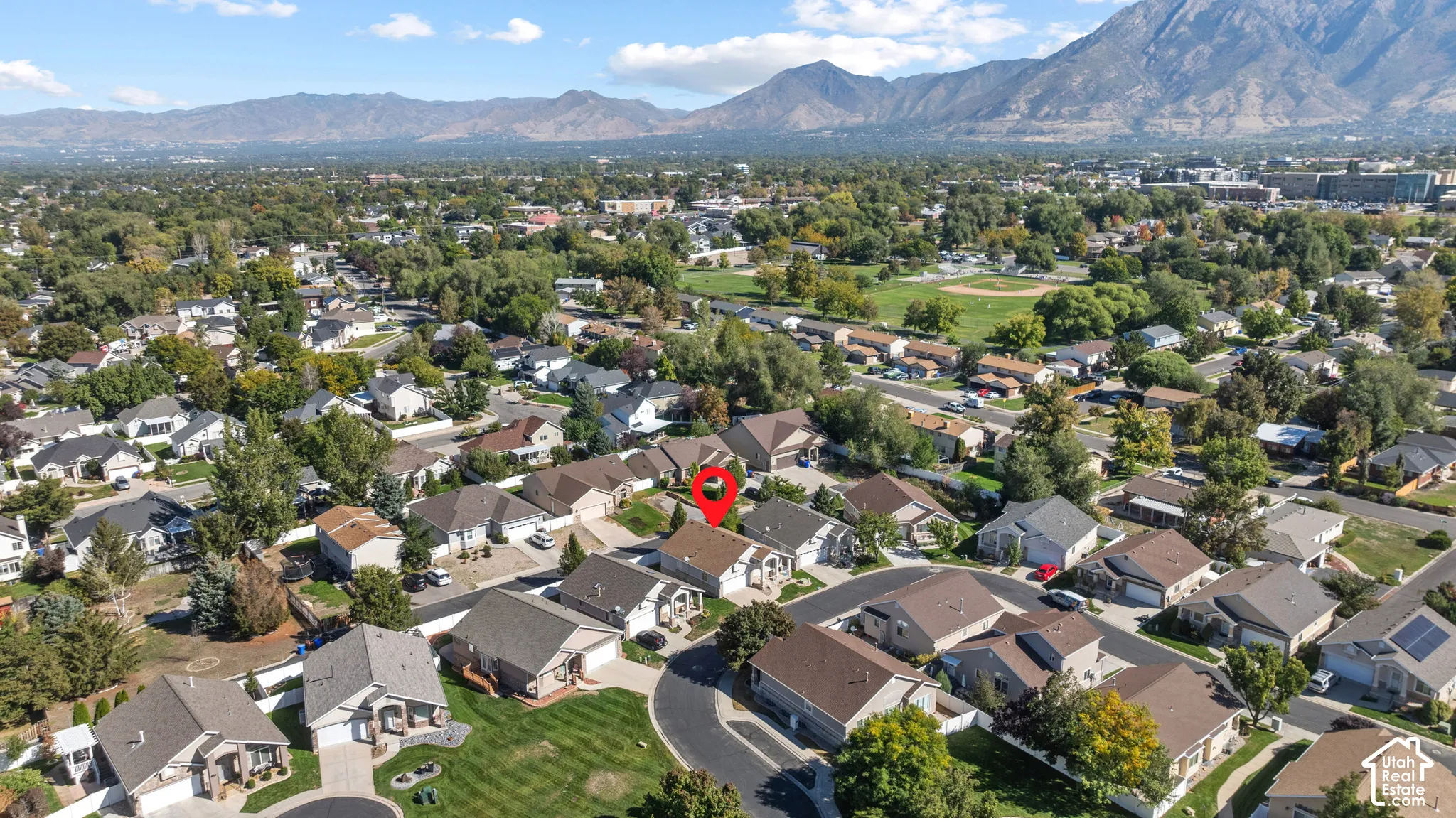 Aerial perspective featuring residential property with mountain backdrop, established tree canopy, and suburban setting