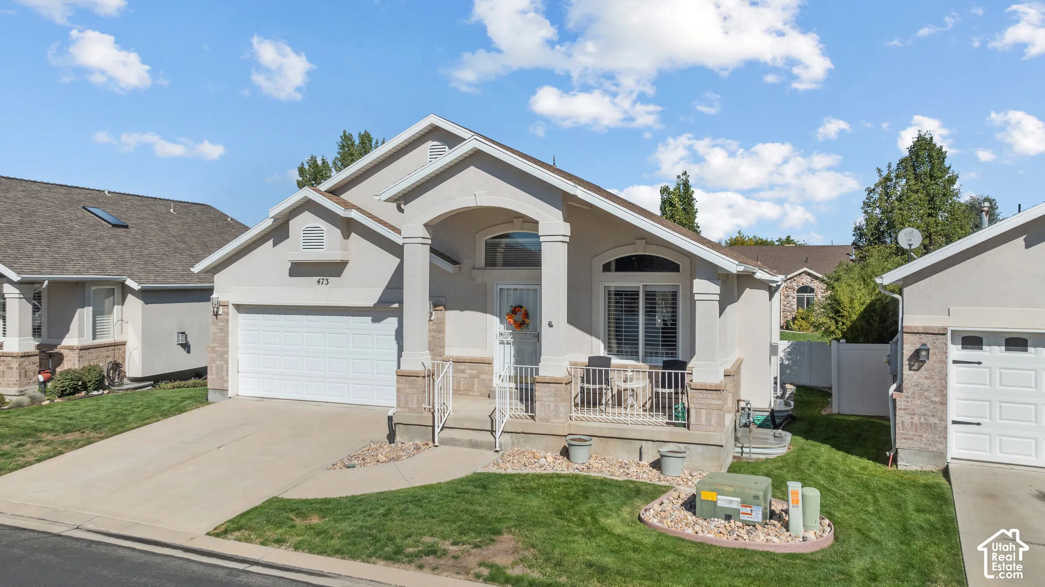 Single-story residence featuring a stucco and stone veneer facade, a covered front porch with arched columns, and an attached two-car garage