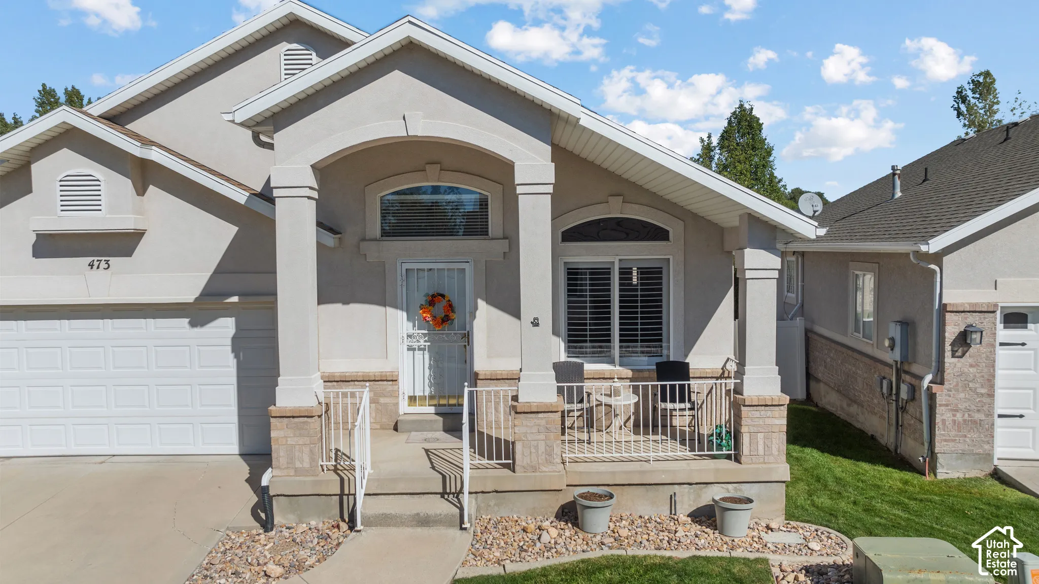 Exterior featuring stucco siding, stone masonry accents, a covered front porch with pillar supports, and an arched transom window