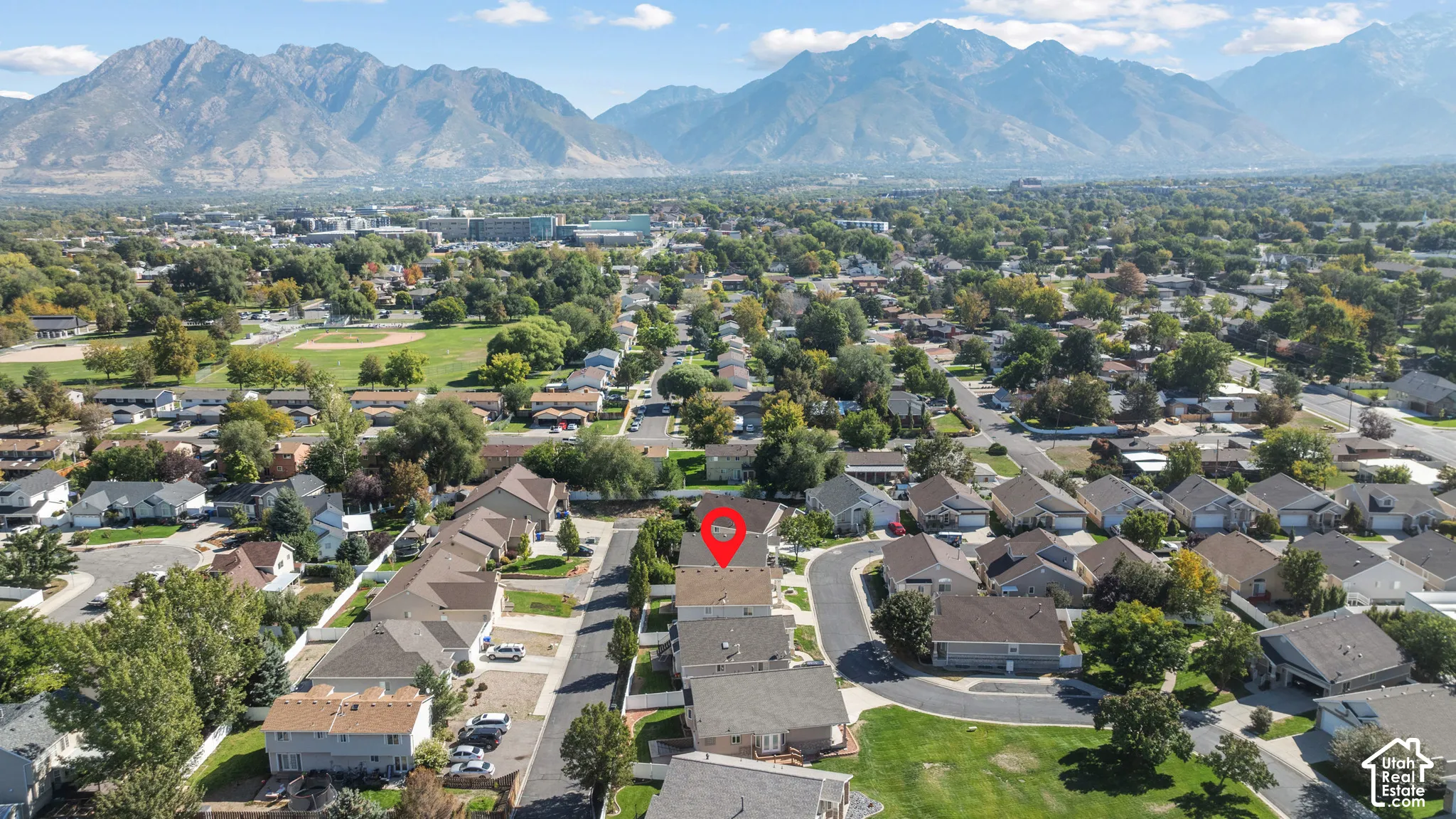 Aerial perspective of a multi-story residence situated within a suburban residential community featuring a backdrop of expansive mountain ranges