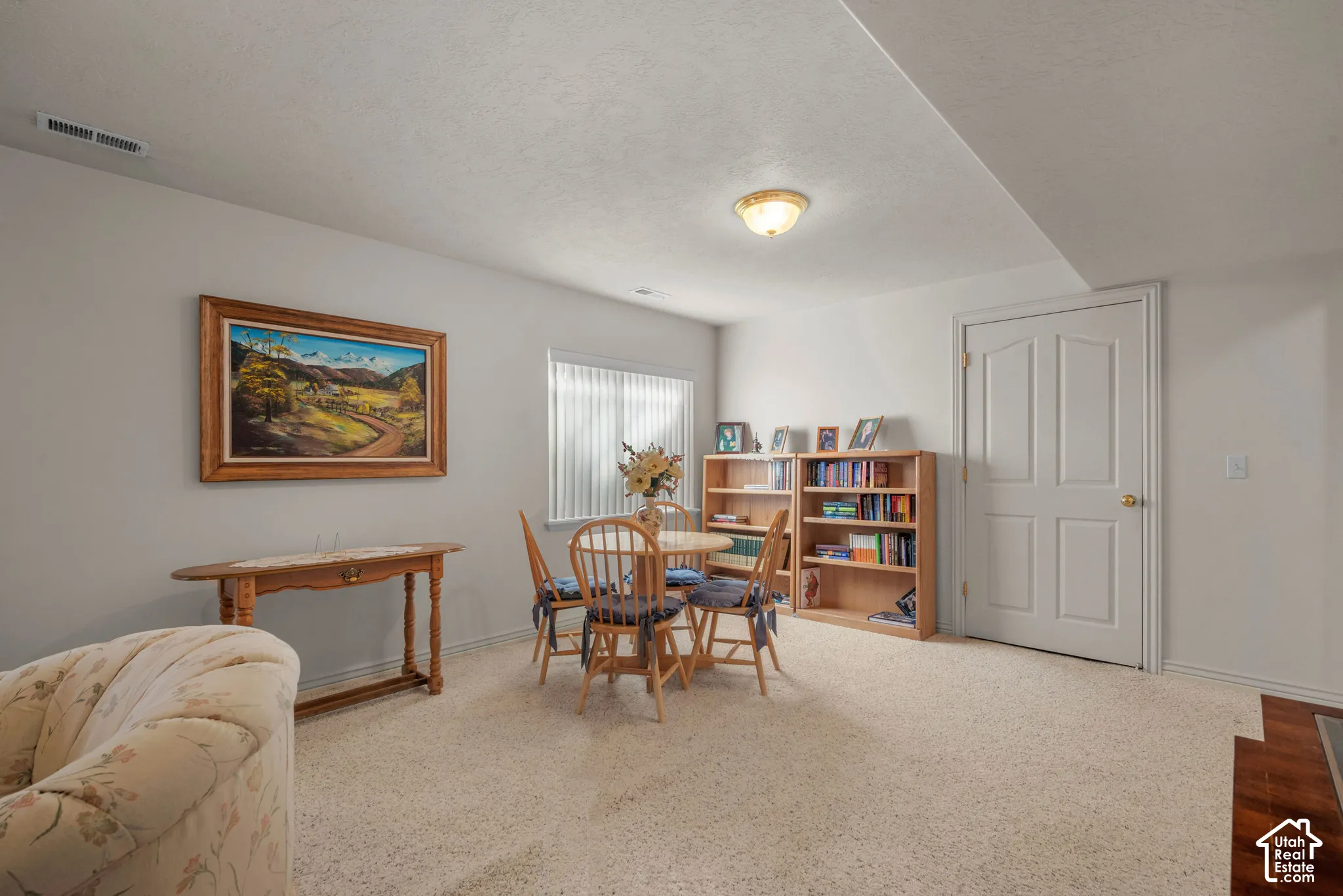 Interior space featuring neutral wall tones, wall-to-wall carpeting, an arched-panel interior door, and a single window with vertical blinds
