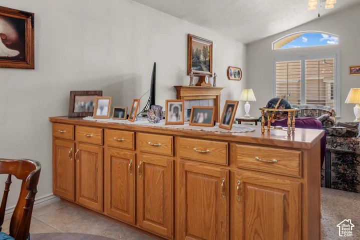 Built-in wood cabinetry with a countertop surface, vaulted ceiling, and arched window