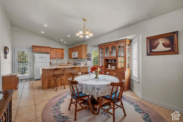 Vaulted ceilings, tile flooring, built-in wooden cabinetry, recessed lighting, and a multi-light chandelier