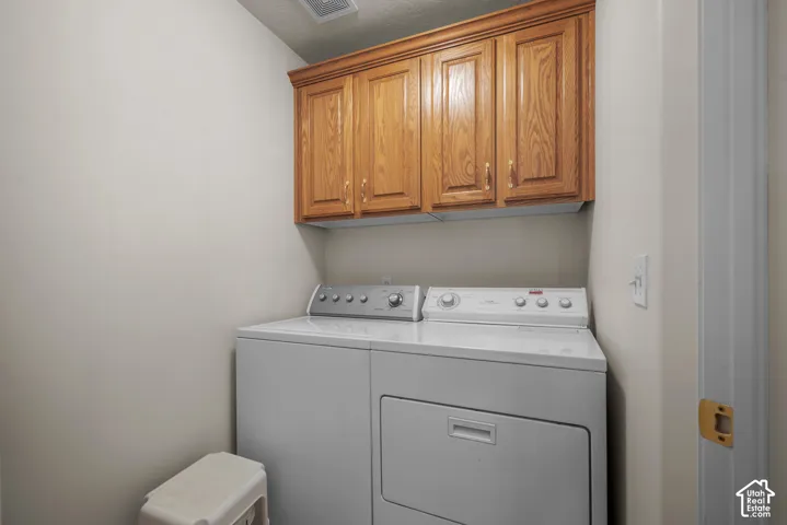 Utility space featuring wall-mounted wood-finish cabinetry with raised-panel doors