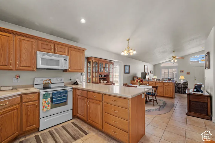 Kitchen featuring wood cabinetry, a peninsula with stone-finish countertops, tile flooring, and vaulted ceilings