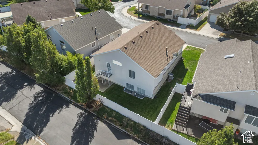 Two-story residence featuring a light-toned exterior, asphalt shingle roof, enclosed lawn, and a private rear deck