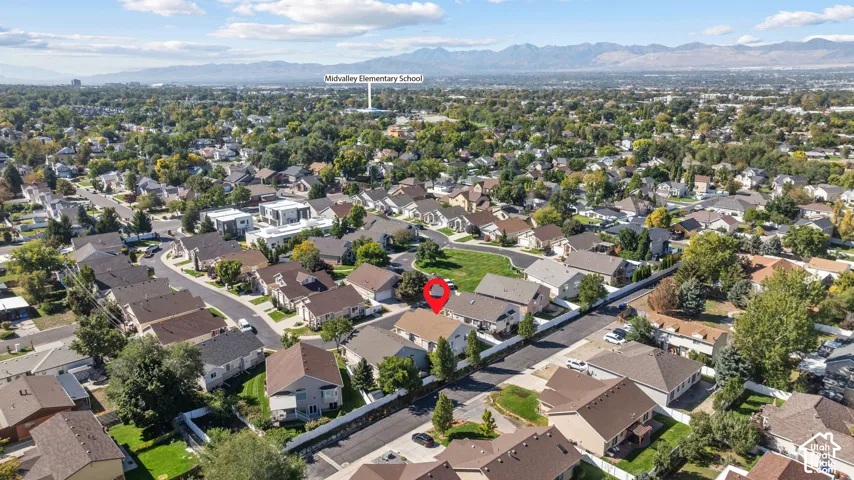 Aerial perspective featuring a residential property with a fenced backyard, asphalt shingle roofing, and a mountain range backdrop