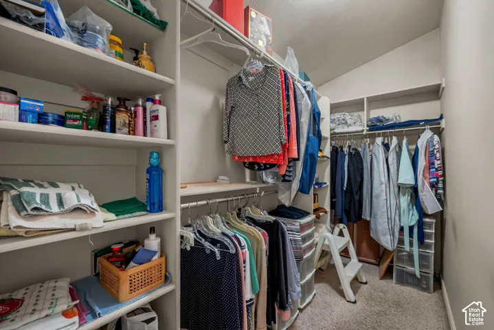 Walk-in storage space featuring built-in white shelving and tiered hanging rods