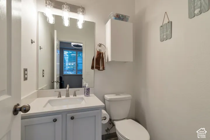Vanity featuring a white countertop with an integrated rectangular sink, three-light fixture, wall-mounted cabinetry, and polished chrome hardware