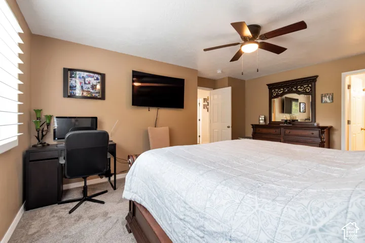 Neutral-toned bedroom featuring carpeted flooring, a ceiling fan with integrated lighting, and white horizontal blinds
