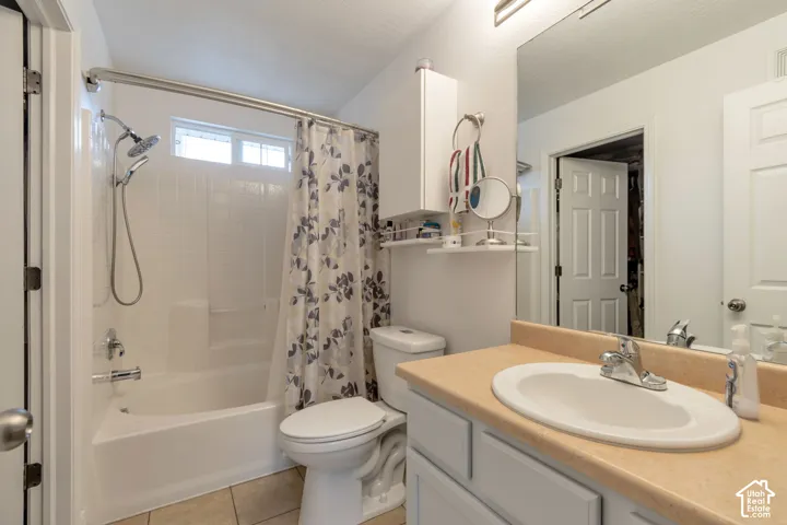 Bathroom featuring a vanity with a solid-surface countertop and integrated sink, a built-in wall cabinet, and a bathtub with a shower head and handheld attachment