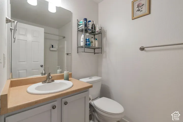Bathroom featuring a vanity with a solid-surface countertop, an integrated oval sink, a chrome faucet, a large wall-mounted mirror, and a multi-light fixture