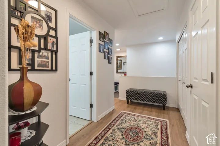 Hallway featuring wood-finish flooring, recessed ceiling lighting, and multiple closet doors with satin-finish hardware