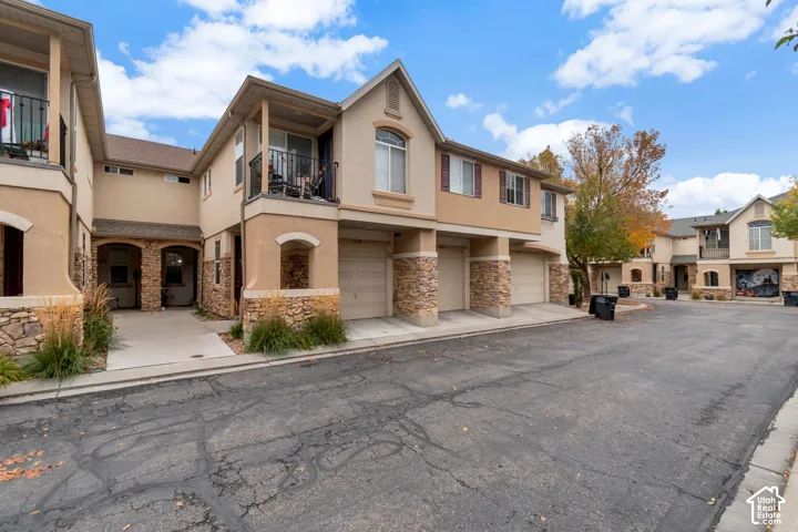 Multi-level exterior featuring stucco siding, stone veneer accents, integrated garages, and second-story balconies