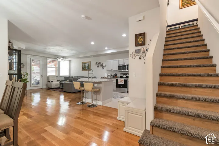 Open-concept interior featuring wood-finish flooring, a kitchen island with stone-finish countertops, recessed lighting, and a staircase with wood-finish treads