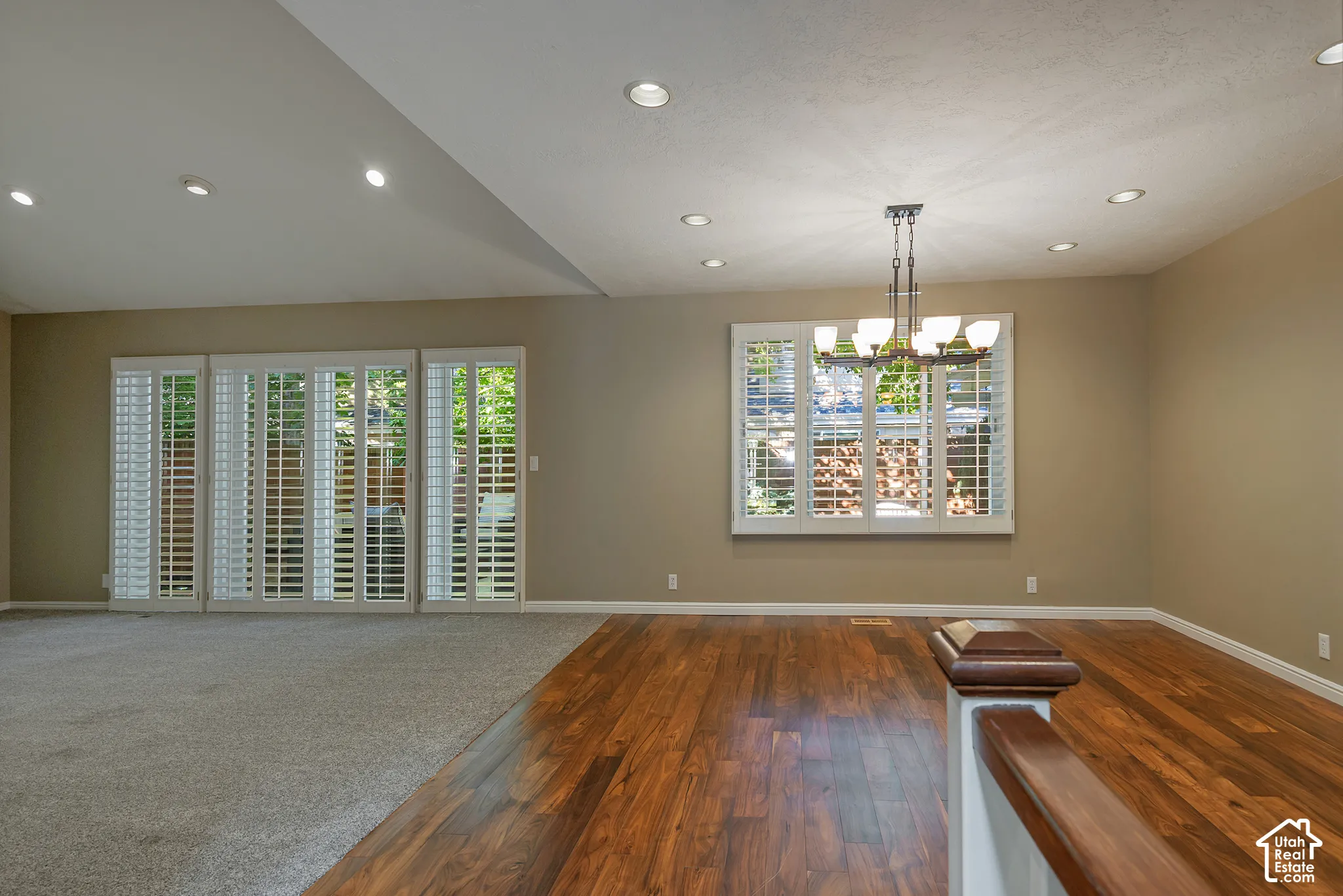 Hardwood-finish flooring, recessed lighting, white plantation shutters, and a multi-bulb chandelier