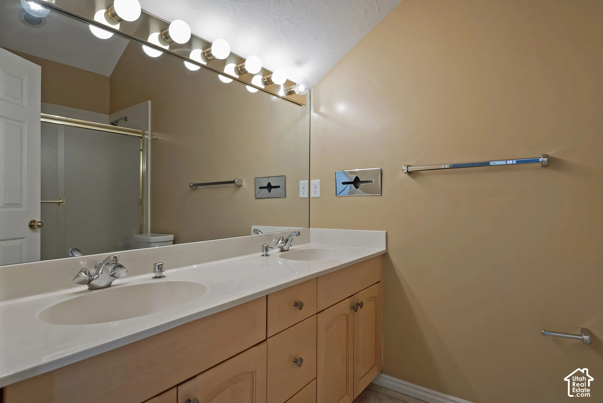 Double vanity with integrated sinks, wood-finish cabinetry, and a full-width mirror