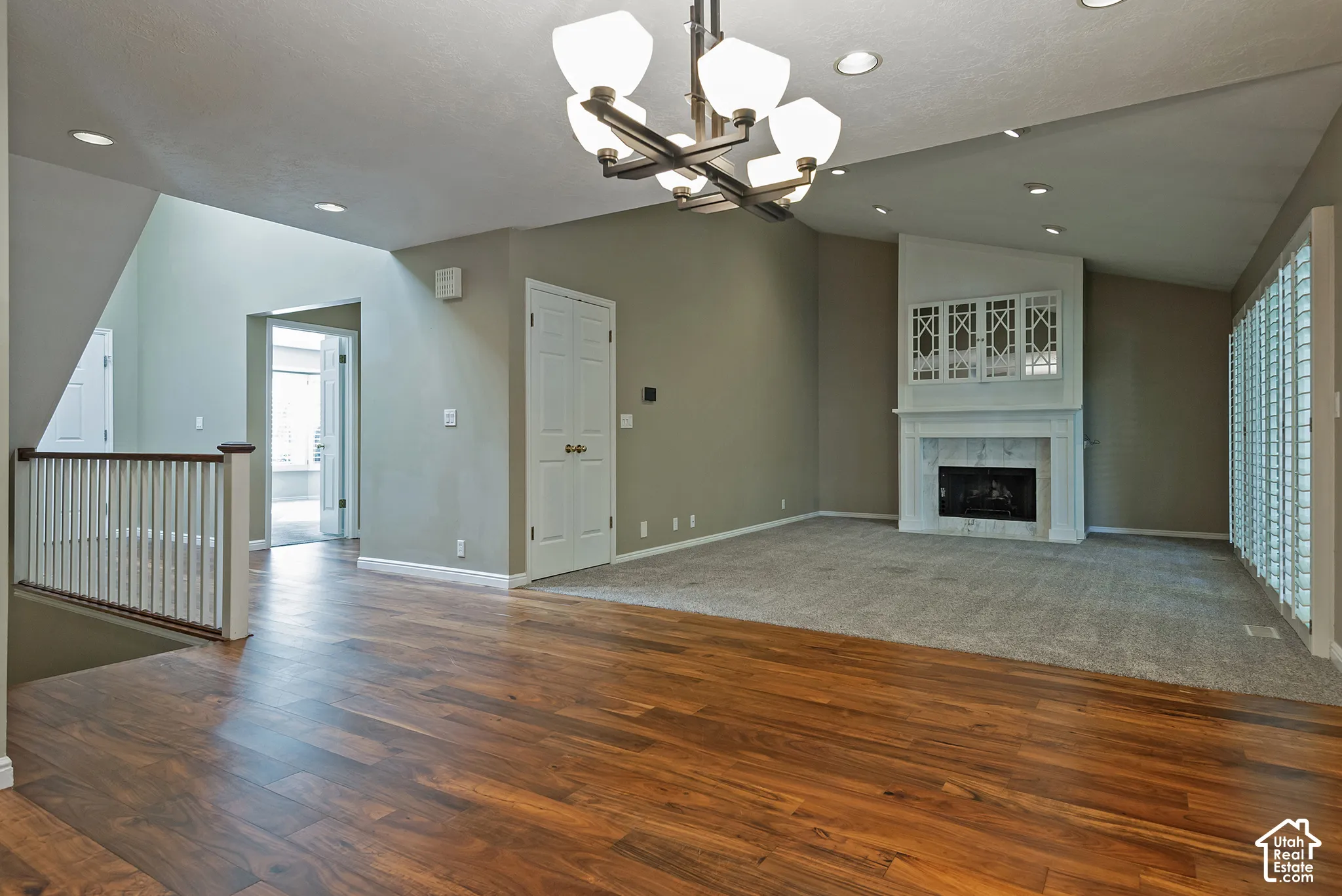 Wood-finish flooring, recessed lighting, and a fireplace with a decorative mantel and marble surround