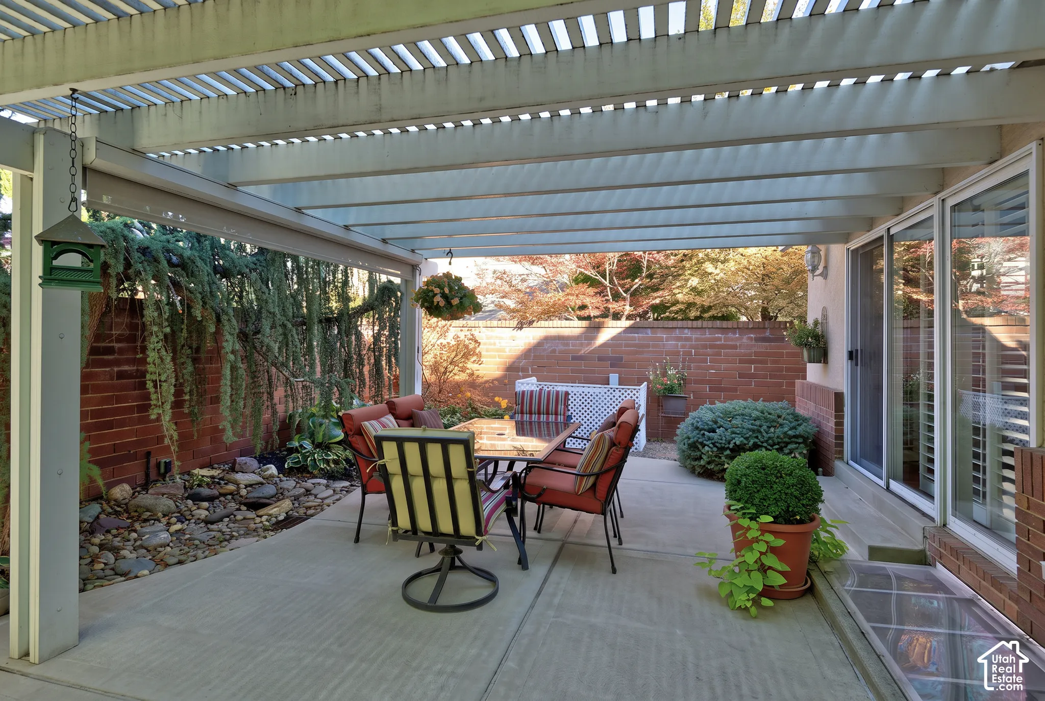 Patio with a slatted pergola, concrete flooring, and a brick privacy wall