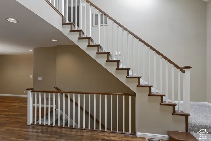 Staircase with wood-finish treads, white balusters, and a rich wood-finish handrail