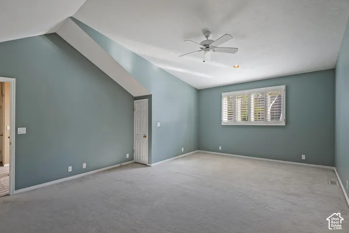 Vaulted ceiling room featuring a ceiling fan, recessed lighting, a window with plantation shutters, and light gray carpeting