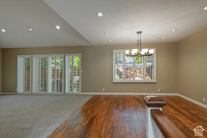 Hardwood-finish flooring, recessed lighting, white plantation shutters, and a multi-bulb chandelier