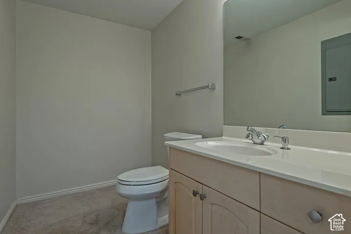 Vanity with light-toned wood-finish cabinetry, integrated sink, and white countertop