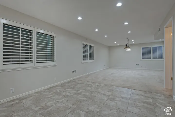 Recessed lighting, plantation shutters, industrial-style pendant fixture, tile flooring, and neutral carpeting