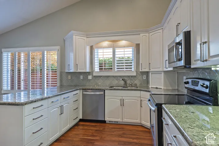 Kitchen featuring white cabinetry with dark pulls, light-toned countertops, stainless steel appliances, and a diagonal tile backsplash
