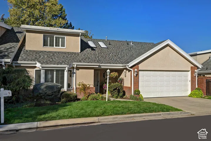 Stucco and brick facade featuring a two-car garage, asphalt shingle roof, and multiple skylights