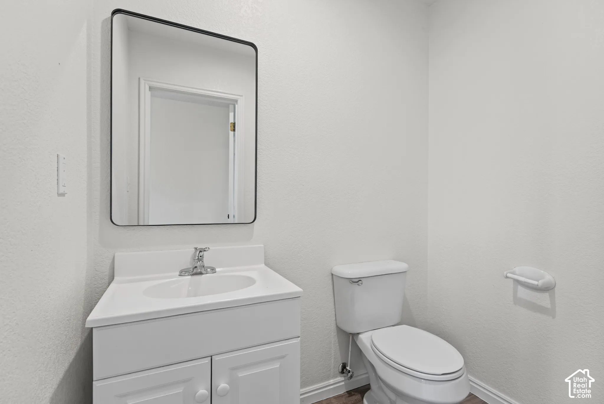 Bathroom featuring a white vanity cabinet with an integrated basin, a single-handle chrome faucet, and a rectangular mirror with a black frame