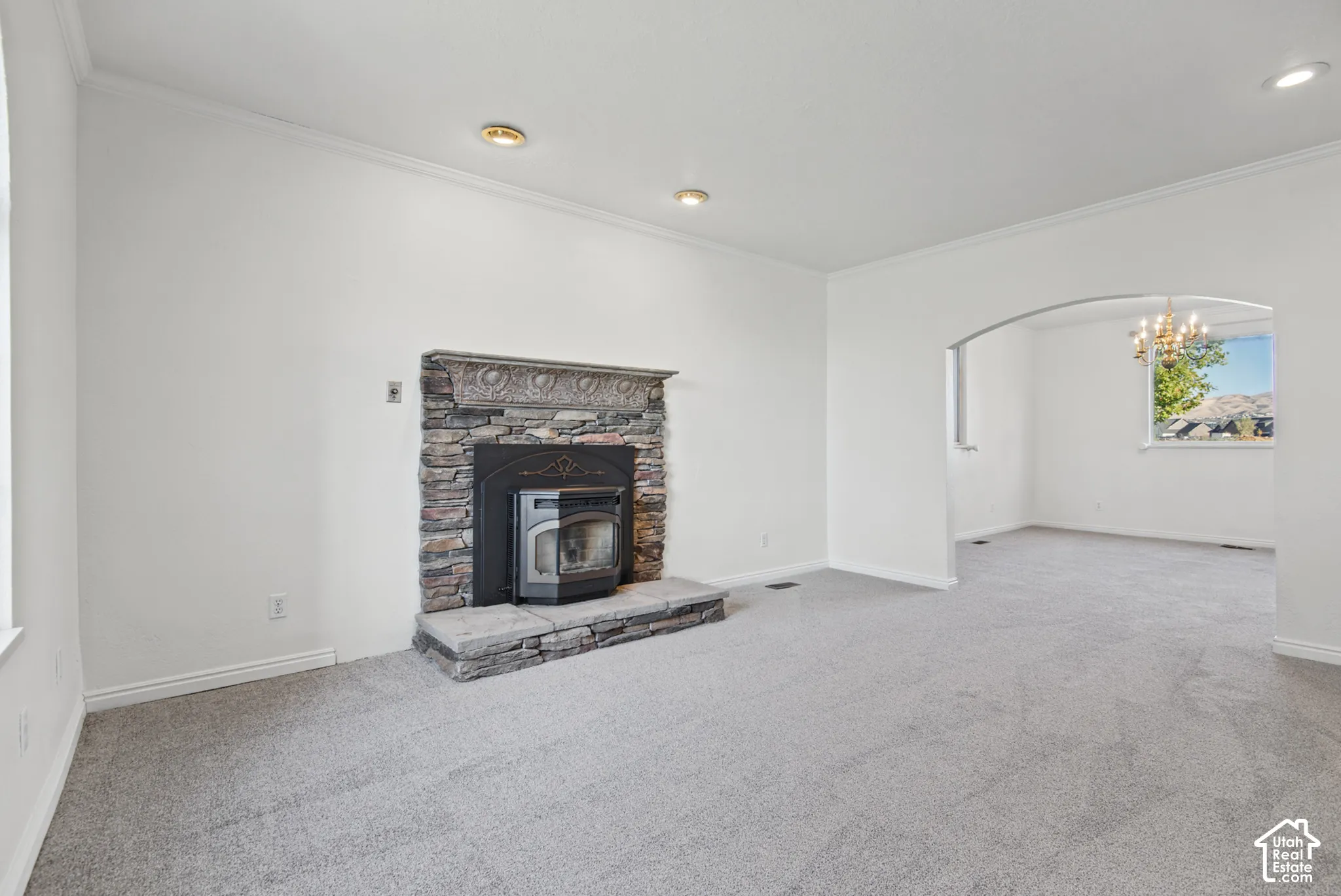 Living area featuring a stone-clad fireplace with a decorative mantel, recessed lighting, and a prominent arched opening