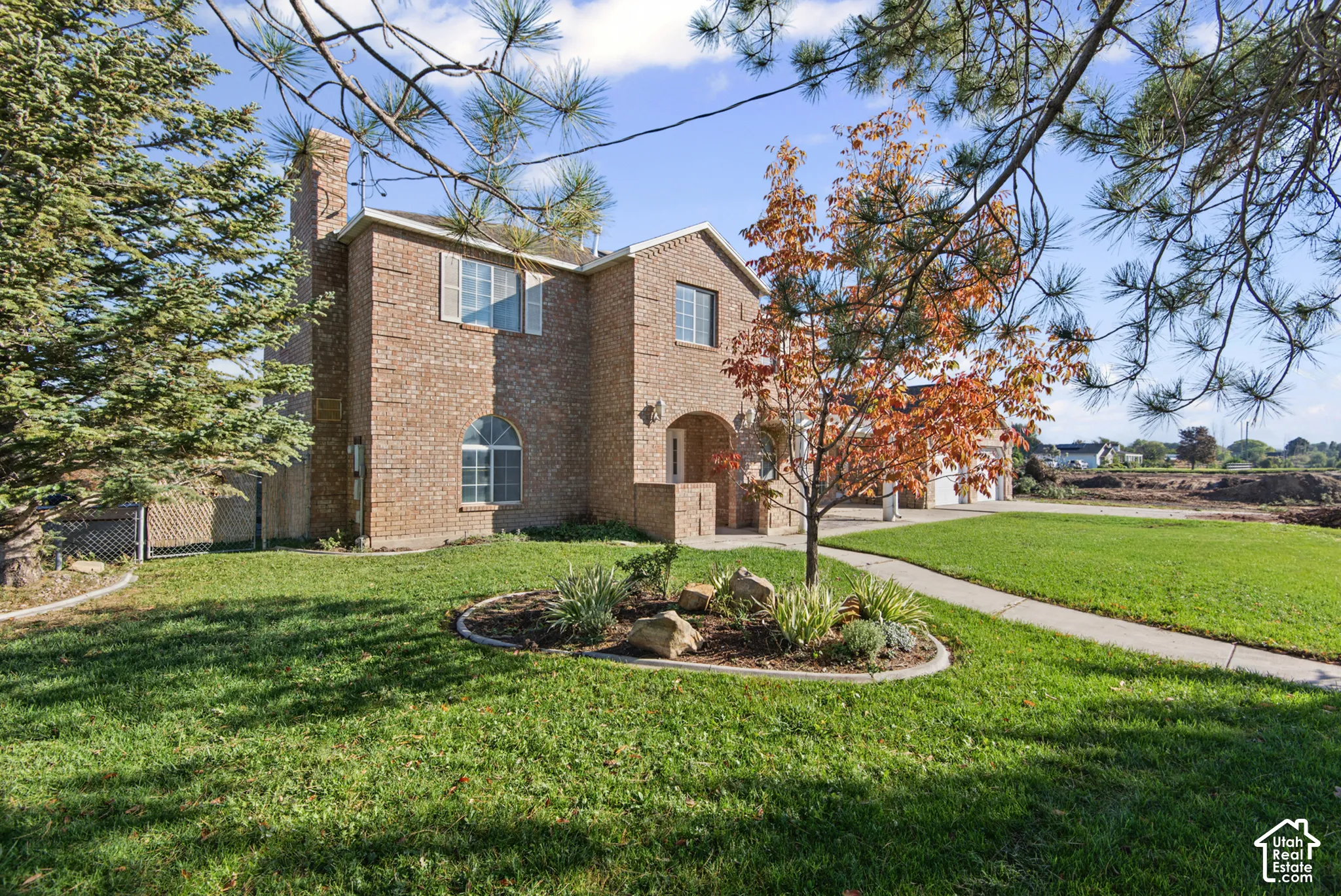 Two-story brick exterior featuring an arched entryway, decorative shutters, a multi-pane arched window, and a paved walkway