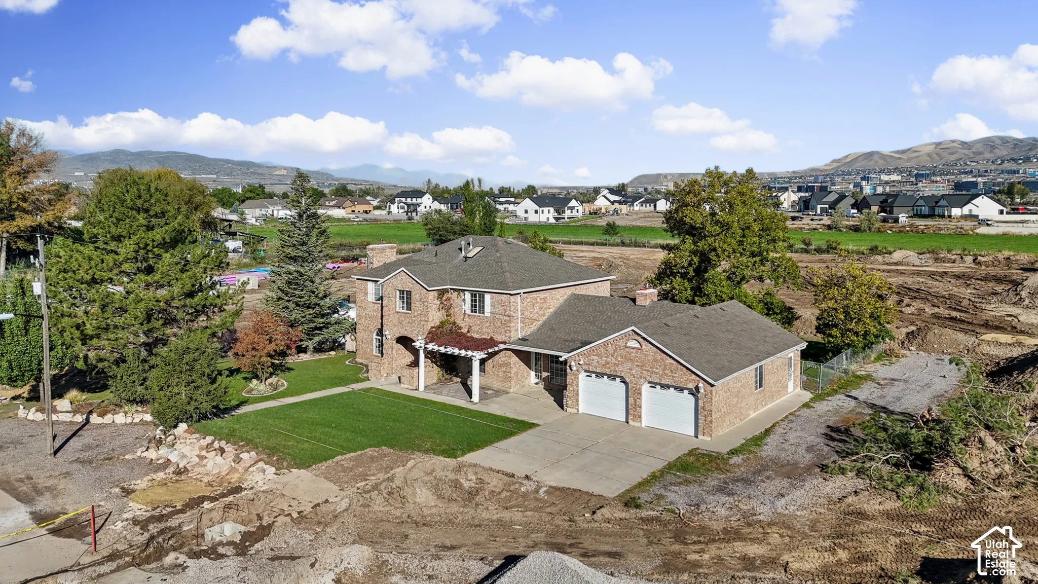 Two-story brick exterior residence featuring a multi-gabled roof, attached two-car garage, and pergola-covered patio area
