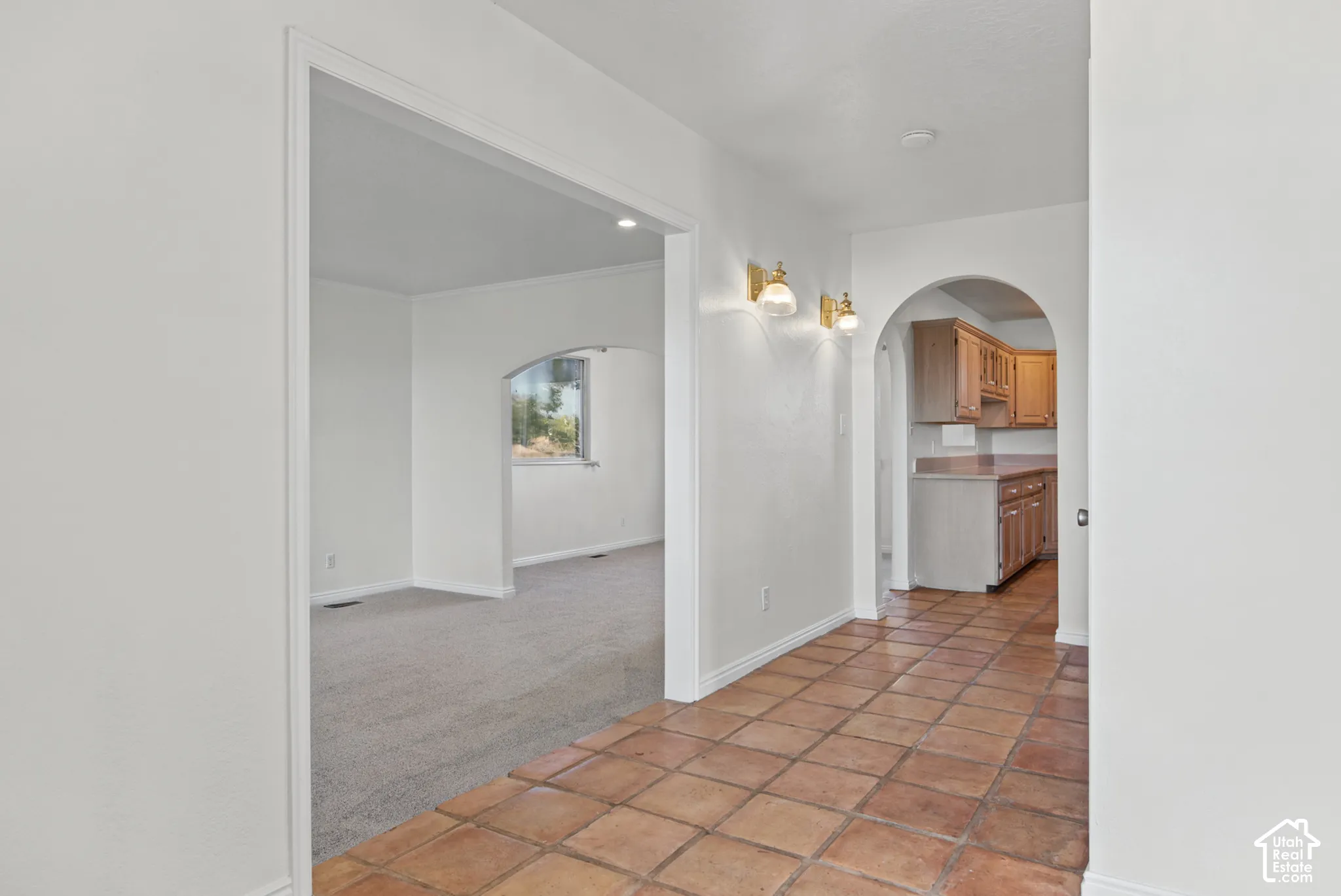 Interior entry featuring earth-toned ceramic tile flooring, arched architectural detailing, wall-mounted light fixtures, and built-in wood cabinetry