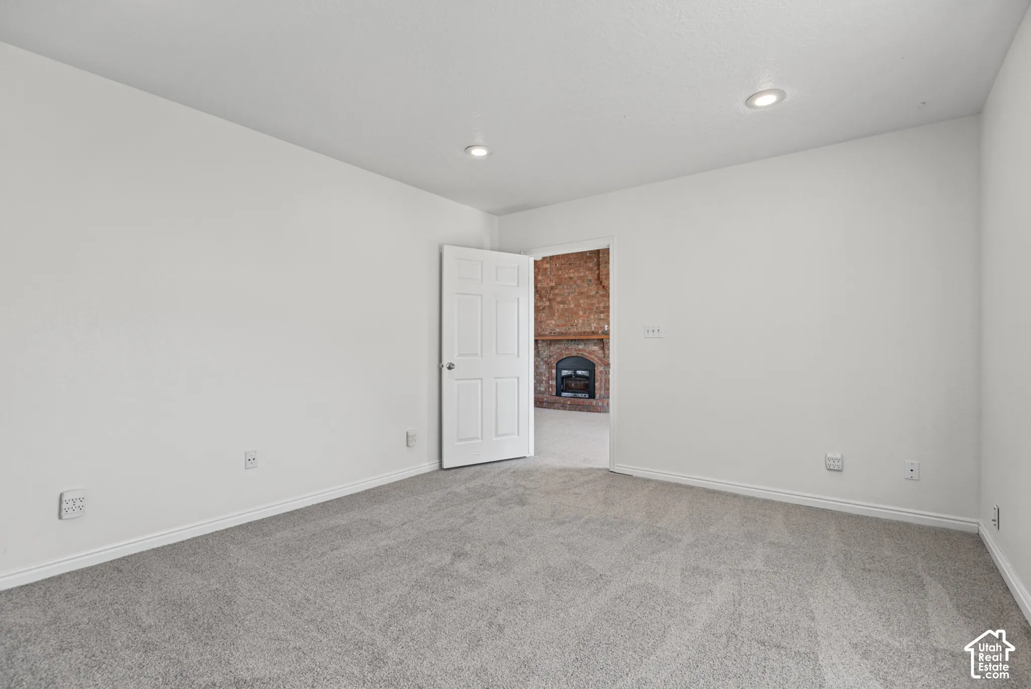 Neutral-toned carpeting, recessed ceiling lighting, and a six-panel interior door
