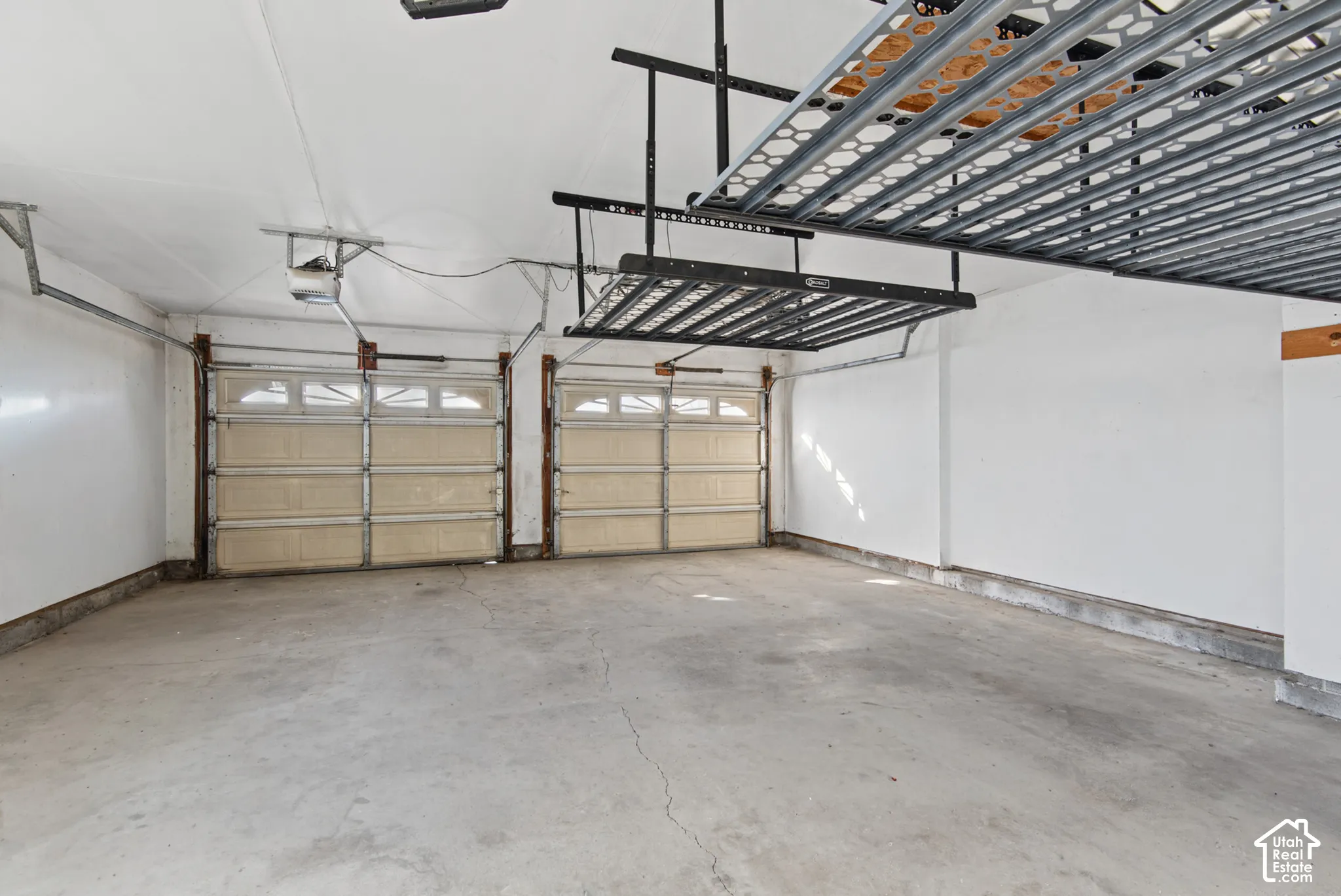 Two-car garage featuring dual overhead paneled doors with transom windows and ceiling-mounted metal storage racks