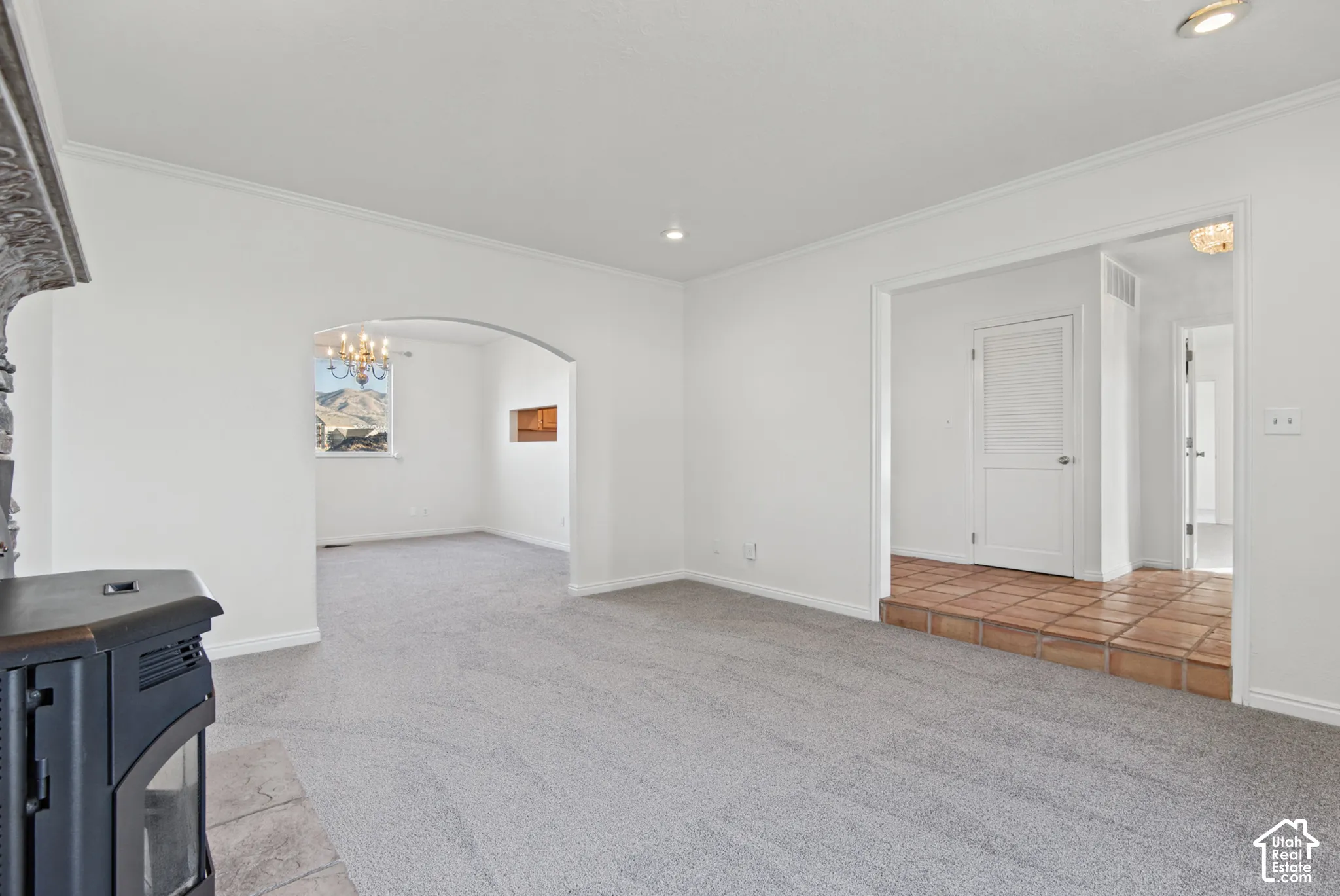 Interior space featuring a cast-iron stove on a stone hearth, arched entryways, recessed lighting, and tile flooring