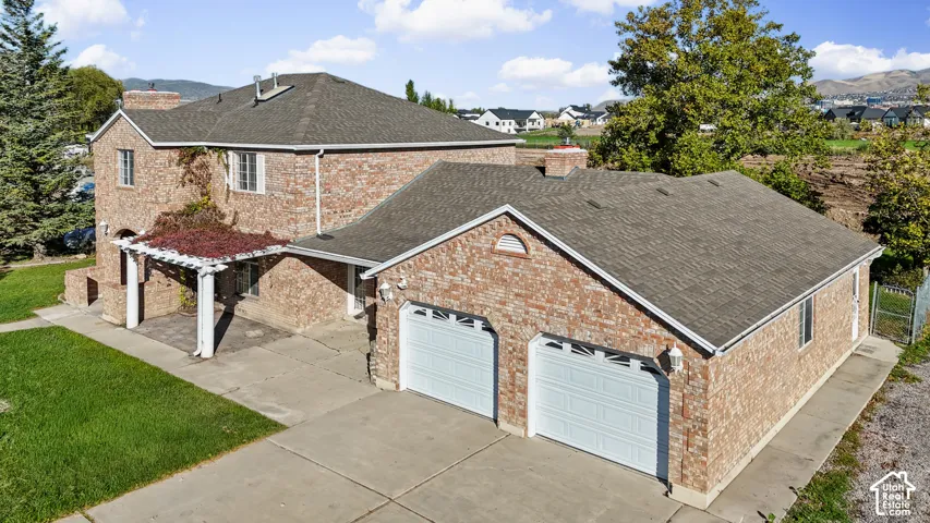 Brick exterior, attached two-car garage, pergola-covered patio, asphalt shingle roof, and concrete driveway