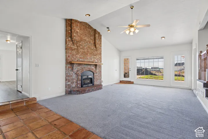 Vaulted ceilings, full-height masonry fireplace with hearth and mantle, terracotta tile flooring, wall-to-wall carpeting, and recessed lighting