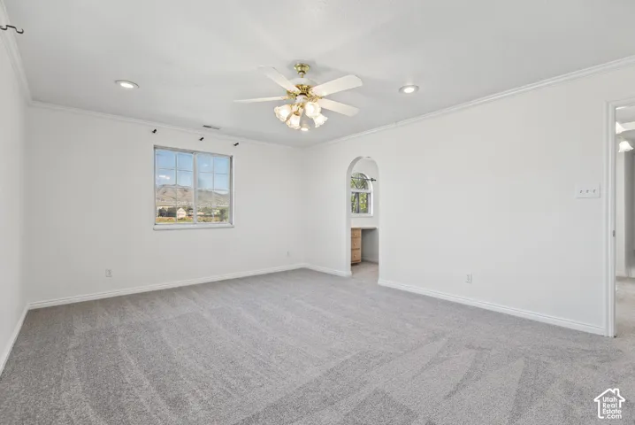 Neutral interior featuring wall-to-wall carpeting, recessed lighting, a multi-blade ceiling fan with integrated lighting, and an arched doorway