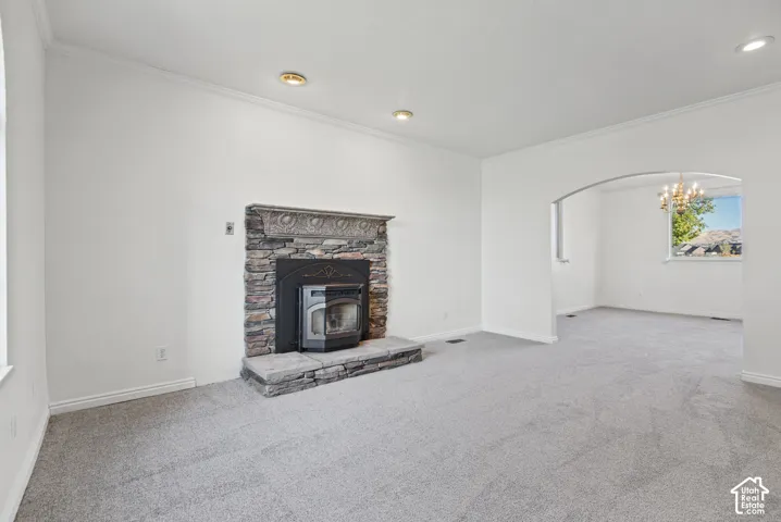 Living area featuring a stone-clad fireplace with a decorative mantel, recessed lighting, and a prominent arched opening