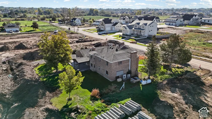 Two-story brick exterior residence featuring a covered patio, mature trees, and a grass-covered lot