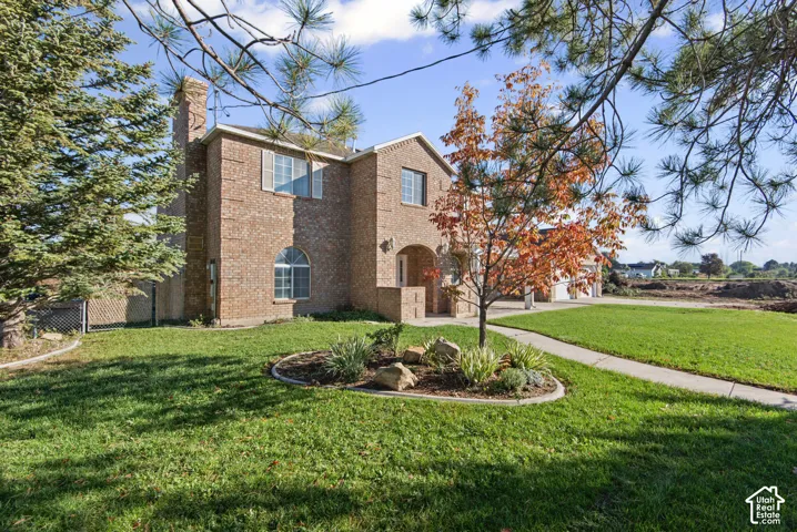 Two-story brick exterior featuring an arched entryway, decorative shutters, a multi-pane arched window, and a paved walkway