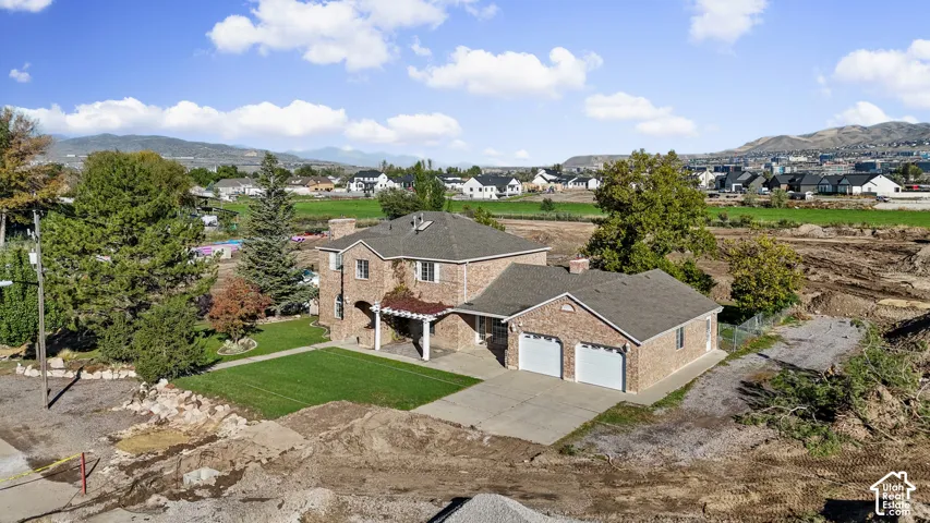 Two-story brick exterior residence featuring a multi-gabled roof, attached two-car garage, and pergola-covered patio area