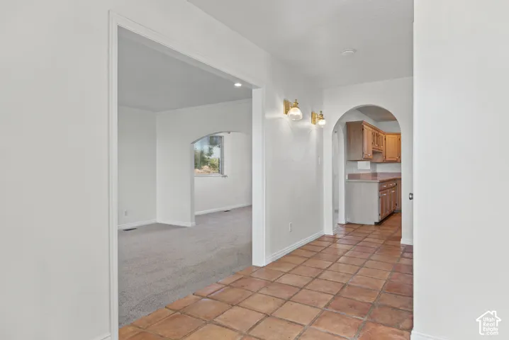 Interior entry featuring earth-toned ceramic tile flooring, arched architectural detailing, wall-mounted light fixtures, and built-in wood cabinetry