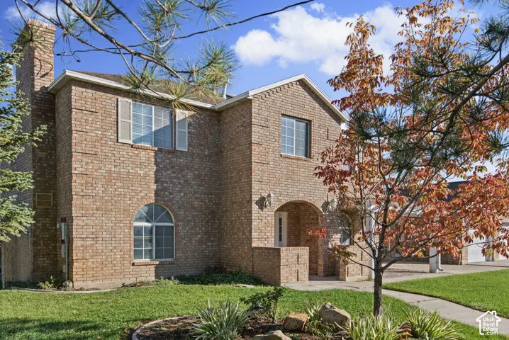 Two-story brick exterior featuring an arched entryway, decorative stone masonry detailing, multi-pane windows, and a chimney stack