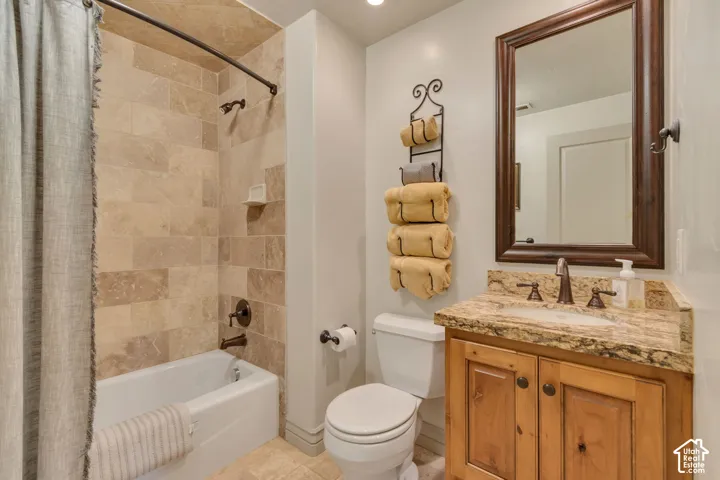 Bathroom featuring a custom wood vanity with stone countertop, tile-surround bathtub, and dark bronze-finish hardware